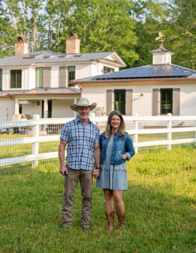 Joyful homeowners in front of their charming farmhouse.